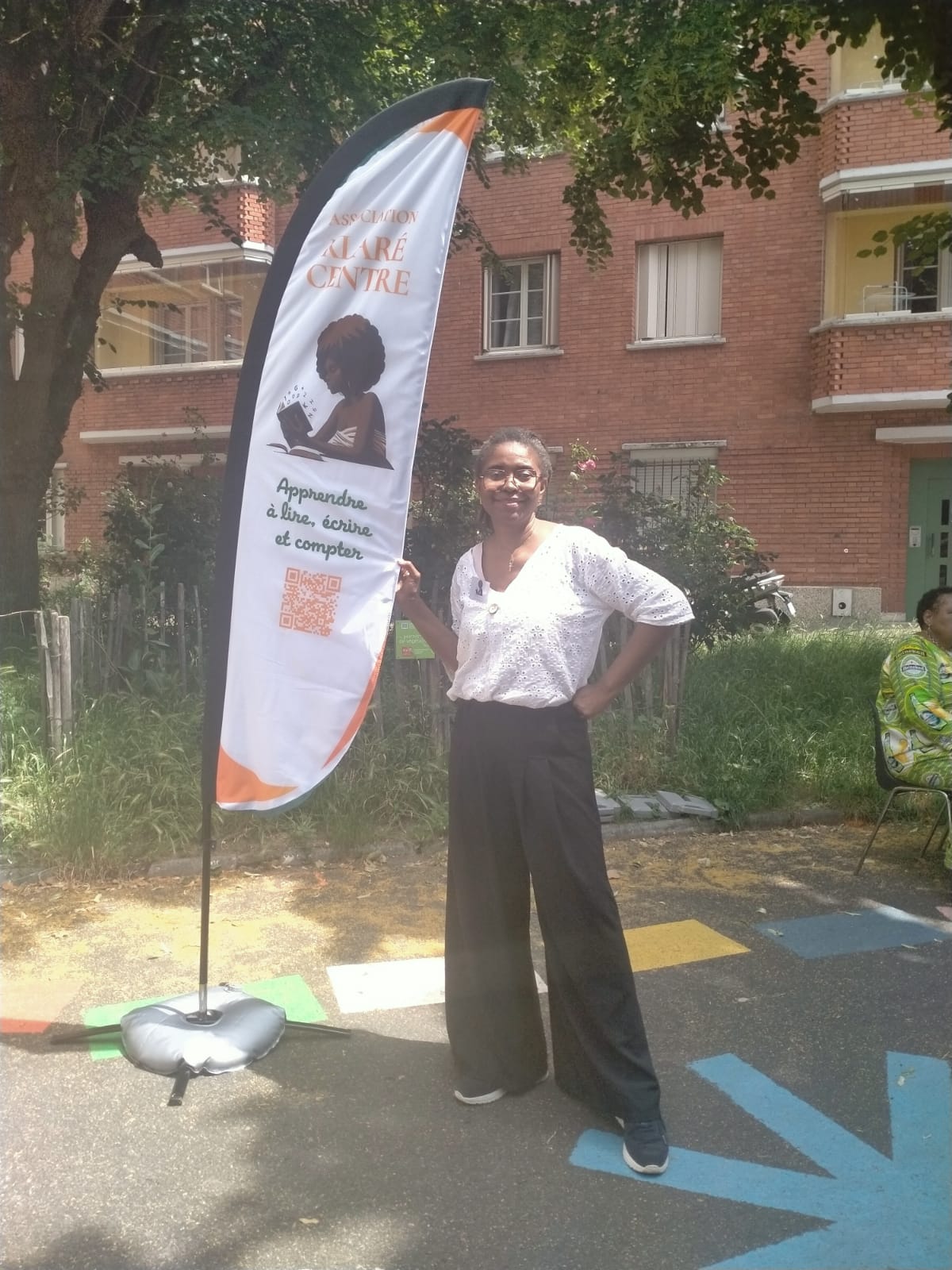 Pose d'une bénévole à côté du drapeau promotionnel