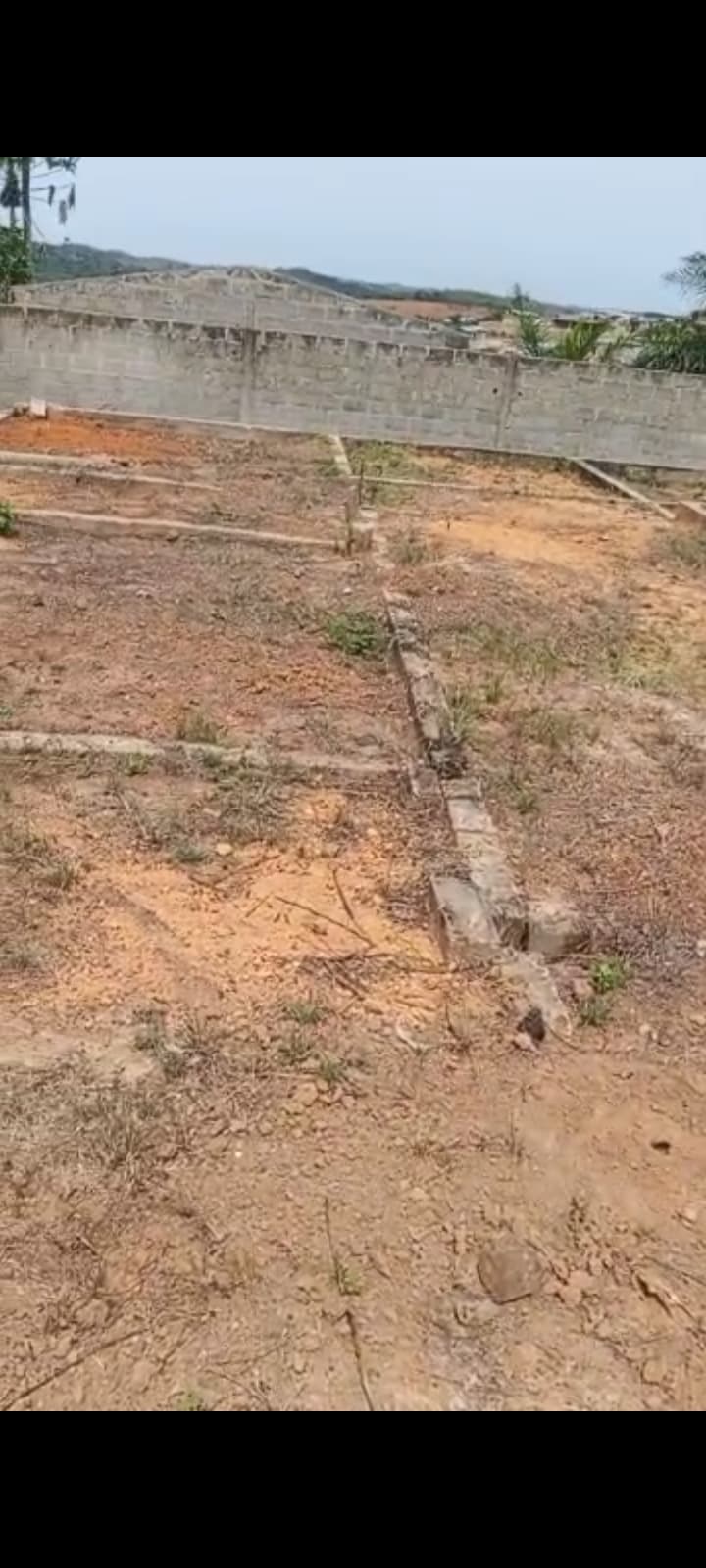 Vue d'ensemble du grand terrain déblayé pour le chantier avec un ouvrier au loin