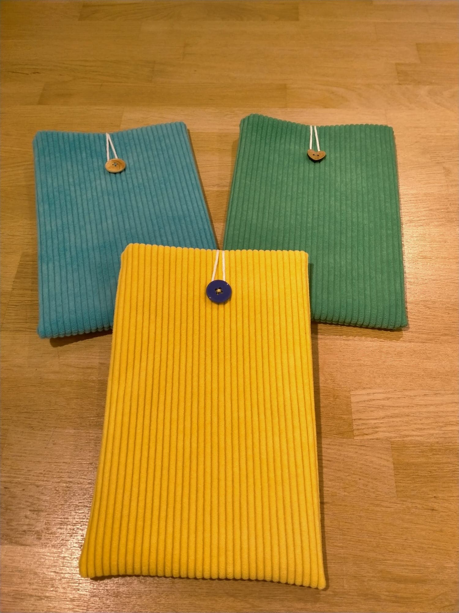 Trois pochettes en velours côtelé de couleurs bleue, verte et jaune avec fermeture à bouton